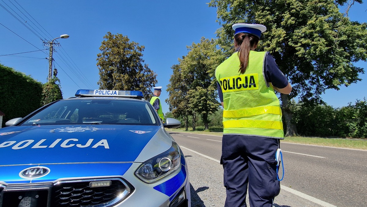 policjanci ruchu drogowego przed oznakowanym radiowozem