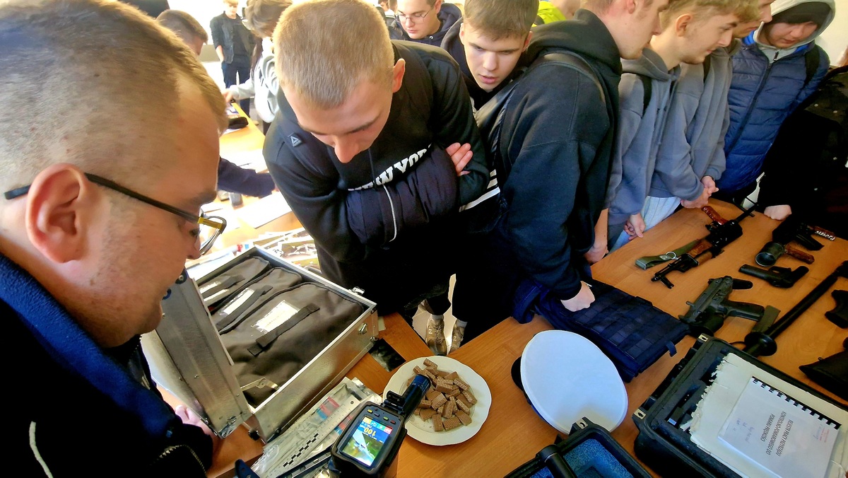 policjant tłumaczący uczniom zasadę działania recznego miernika prędkości