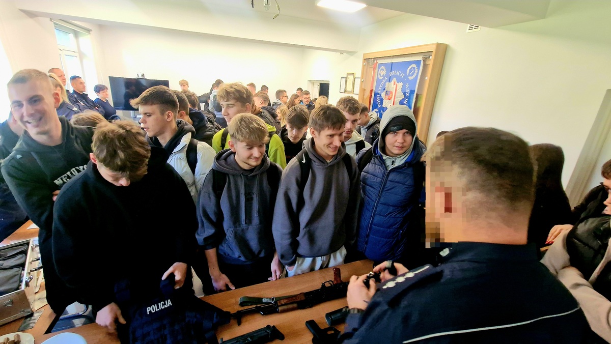 funkcjonariusz na stoisku z bronią słuzbową rozmawijący z uczniami