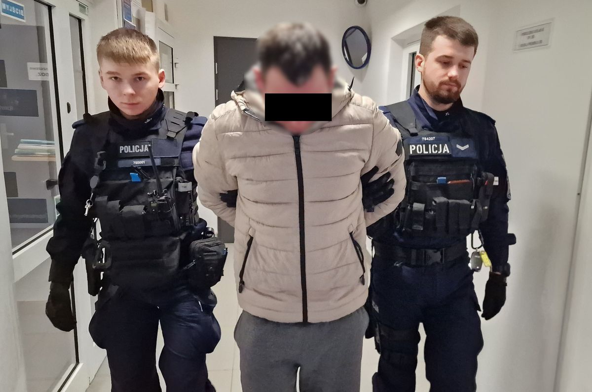 Policjanci prowadzą zatrzymanego mężczyznę.