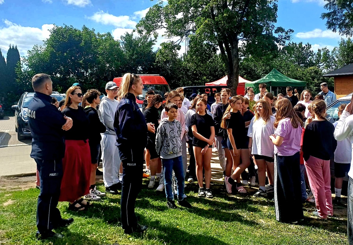 policjanci i grupa dzieci przy oznakowanym radiowozie