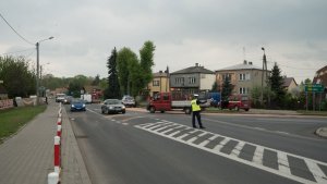 Policjant ręcznie kieruje ruchem na skrzyżowaniu.