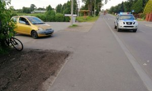 Po prawej stronie na parkingu przed sklepem żółta toyota yaris. Obok na ulicy Kolejowej policyjny radiowóz z włączonymi sygnałami świetlnymi