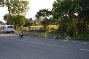 Policjant techik kryminalistyki zabezpieczający z jezdni ślady w postaci elementów motocykla