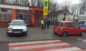 Uszkodzone pojazdy marki Volkswagen oraz Renault zaparkowane na chodniku przy przejściu dla pieszych.