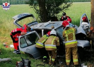 Uszkodzony pojazd marki Volkswagen Golf w przydrożnym rowie. Obok pojazdu ratownicy medyczni oraz strażacy.