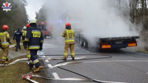 palaca sie ciezarówka i strażacy podczas akcji ratowniczo - gaśniczej