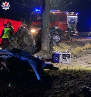 rozbity pojazd w tle policjant strażak i wóz strażacki