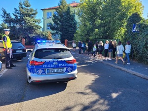 policjant rd przy oznakowanym radiowozie w rejonie przejscia dla pieszych