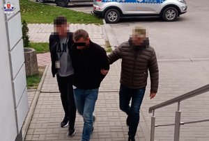 zatyrzymany mężczyzna doprowadzany przez nieumndurowanych policjantów