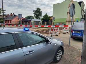 wykop zabezpieczony taśmą z napisem policja obok stojący oznakowany radiowóz