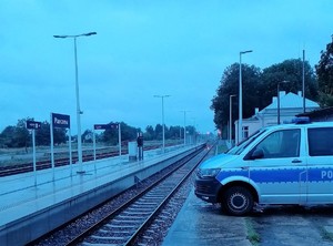 radiowóz oznakowany na tle dworca kolejowego