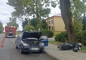 na zdjęciu widoczny jest radiowóz , samochód osobowy i lezący na chodniku motorower