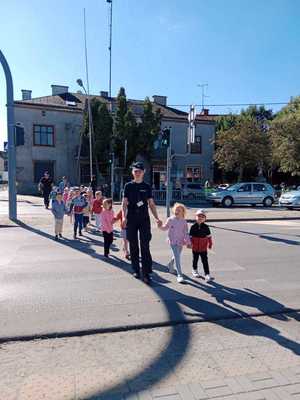 policjantka z przedszkolakami przechodzi przez przejście dla pieszych