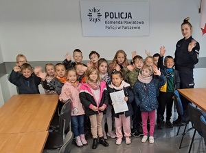 na zdjęciu znajdują sie dzieci i policjantka . A za nimi widnieje napis Komenda Powiatowa Policji w Parczewie