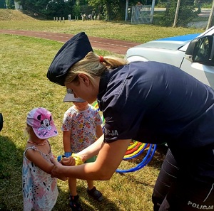 policjantka zakładająca dzieciom opaski odblaskowe na ręce