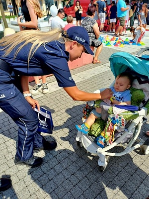 policjantka dająca dziecku w wózku lizaka