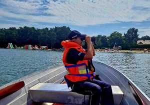 policjantka obserwująca plażowiczów przy pomocy lornetki