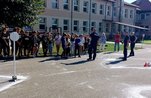 grupa uczniów z policjantem prowadzącym prelekcję