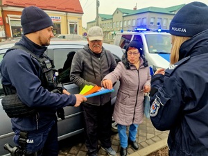 policjant i policjantka wreczającyc ulotki i odblaski