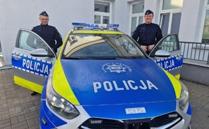 policjanci przy oznakowanym radiowozie