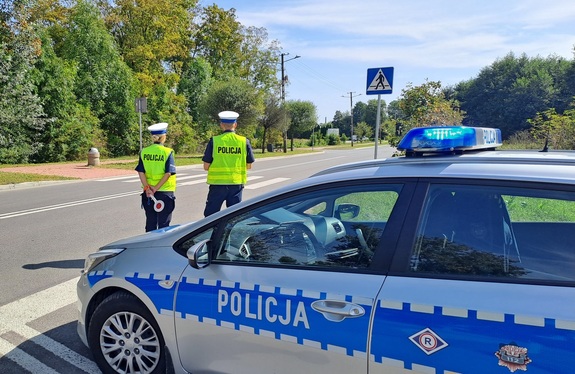 policjanci przed oznakowanym radiowozem
