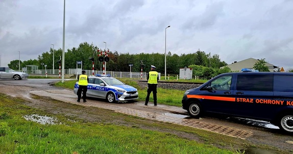 policjant i funkcjonariusz straży ochrony kolei w rejonie przejazdu kolejowego