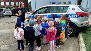 zdjęcie grupowe policjantki z dziecmi obok radiowozu