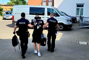 poszukiwany prowadzony przez umundurowanych policjantów, zdjęcie zrobione od tyłu