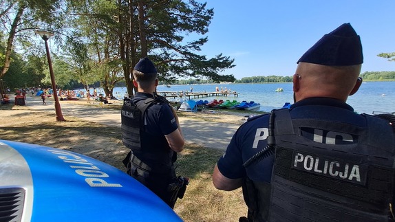 policjanci przy radiowozie na tle plaży