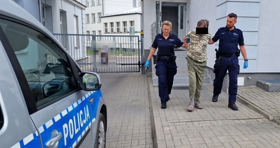 umundurowani policjanci prowadzący osobę zatrzymaną