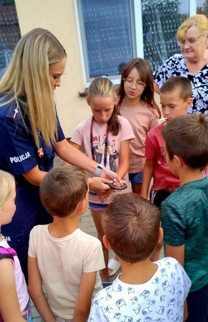 policjantaki z dziećmi pokazująca kajdanki