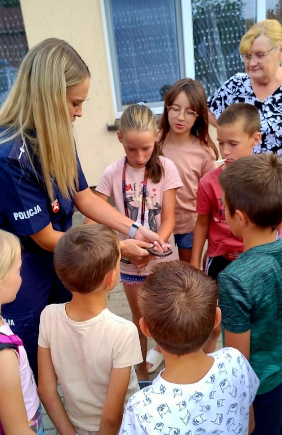 policjantaki z dziećmi pokazująca kajdanki
