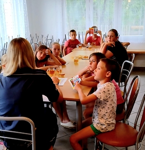 policjantka z dziećmi siedząca przy stole