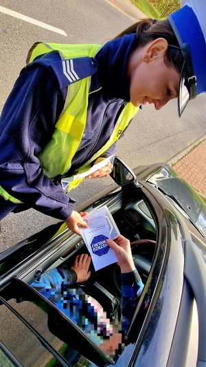 policjantka wręczająca kierowcy ulotkę