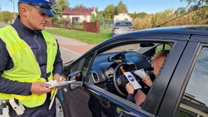 umundurowany policjant wręczający kierowcy ulotkę