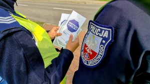 zdjęcie ulotek umieszczonych pomiędzy ramionami policjantów