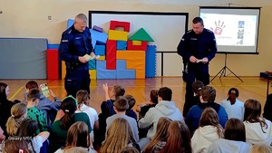 policjanci rozdający uczniom ulotki profilaktyczne