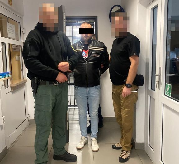 Policjanci doprowadzają zatrzymanego do sprawy rozboju.