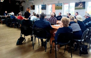 seniorzy siedzący tyłem słuchający prelekcji policjantki