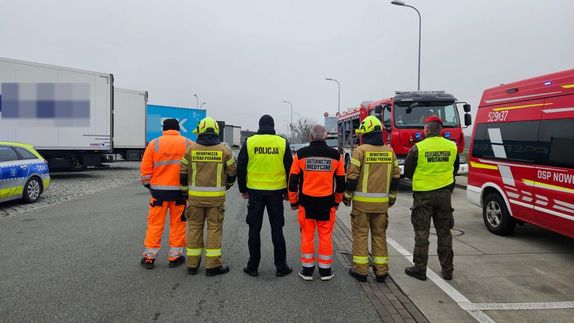 policjanci strażacy i ratownicy medyczni w mindurach staojący tyłem