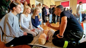 strażak i 3 uczennice siedzące przez fantomem mężczyzny