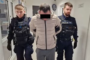 Policjanci prowadzą zatrzymanego mężczyznę.