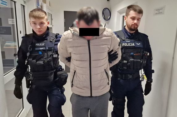 Policjanci prowadzą zatrzymanego mężczyznę.