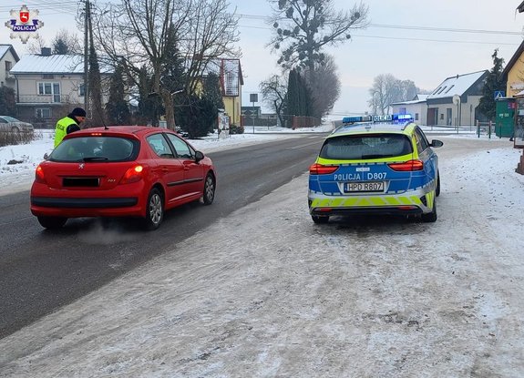 policjant przy czerwonym pojeździe