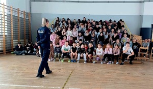 policjanta przed grupą uczniów siedzącą na trybunach