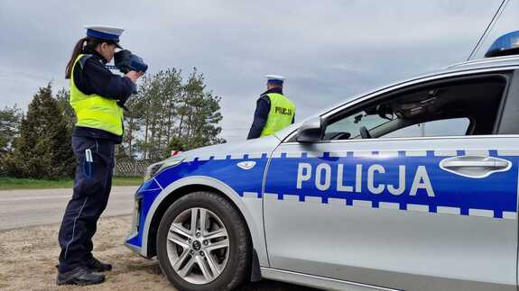 policjant i policjantka przy oznakowanym radiowoziwe