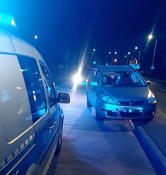 zatrzymany szary pojazd stojący obok oznakowanego radiowozu