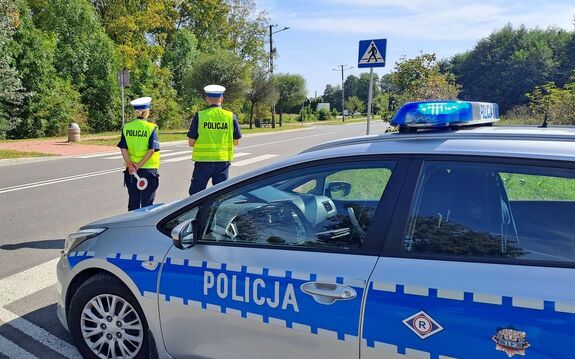 policjanci przed oznakowanym radiowozem