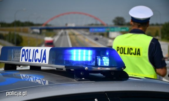 poliocjant tyłem na tle oznakowanego radiowozu